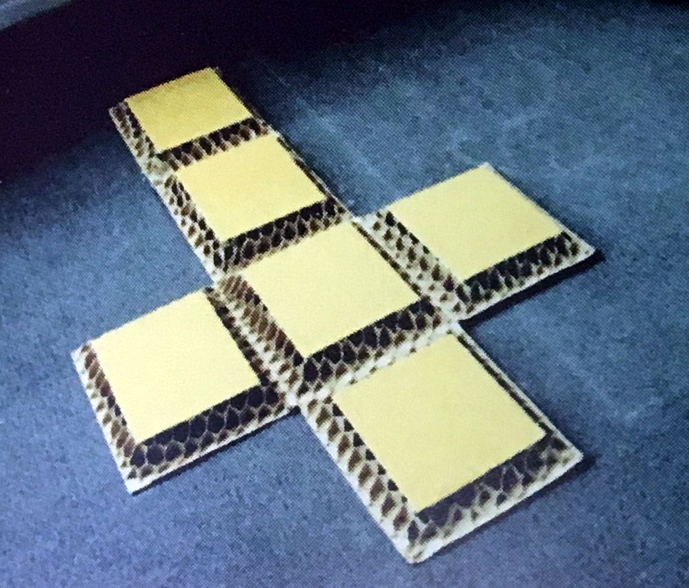 Una cruz hecha con cuadrados de cartón sobre una alfombra