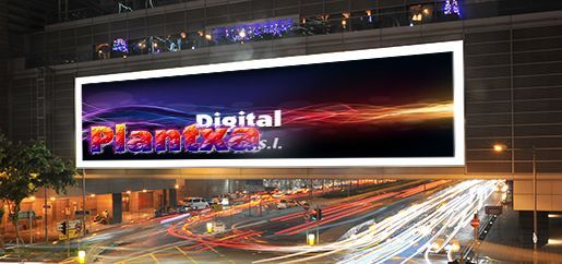 Un gran cartel publicitario cuelga sobre una calle de la ciudad por la noche.