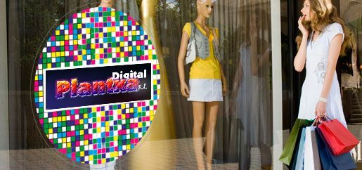 Una mujer está parada frente al escaparate de una tienda sosteniendo bolsas de compras.