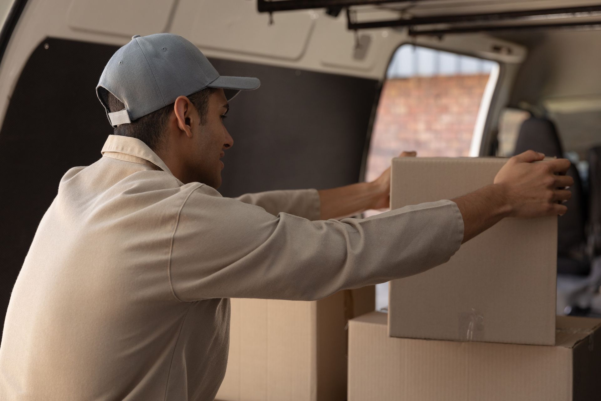 Un repartidor está cargando cajas en la parte trasera de una camioneta.