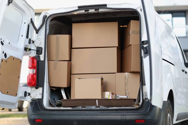 La parte trasera de una camioneta blanca está llena de cajas.