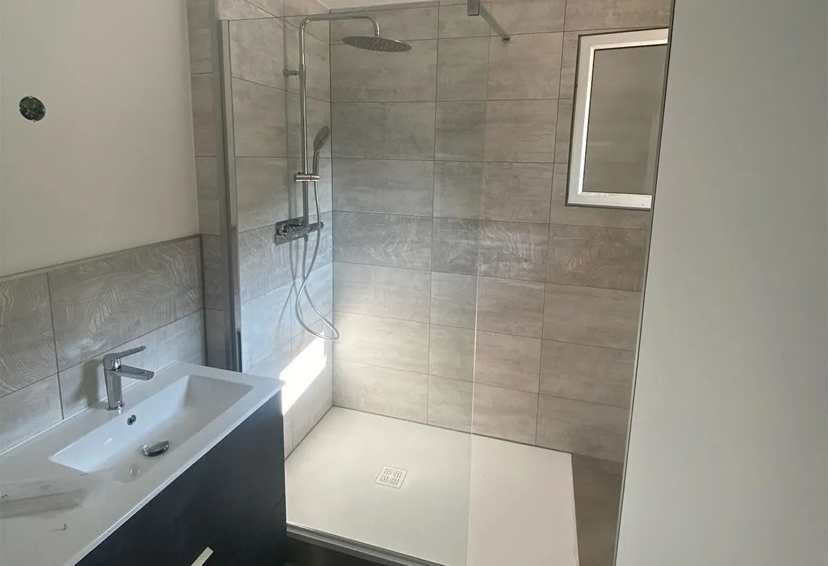 Salle de bains moderne avec lavabo, miroir, douche carrelée et paroi de douche en verre
