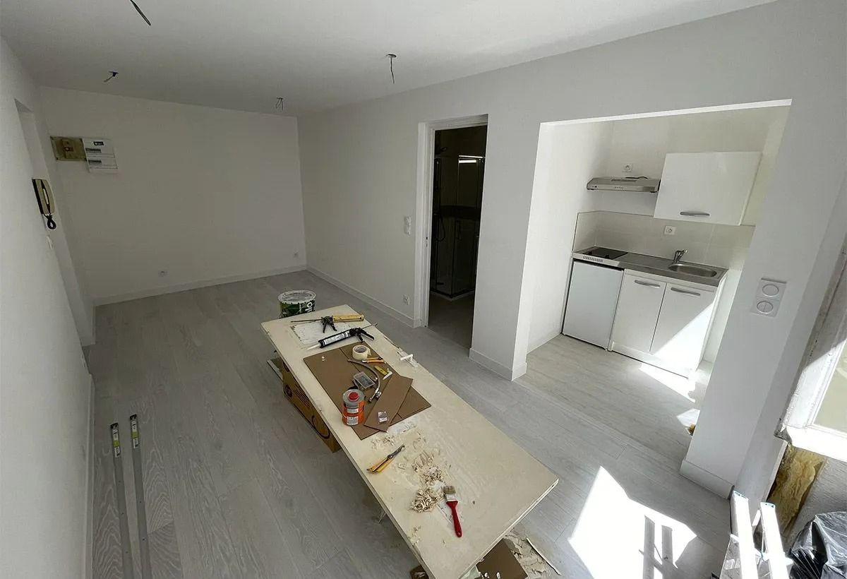 Pièce blanche vide avec une longue table à outils et un petit coin cuisine en arrière-plan