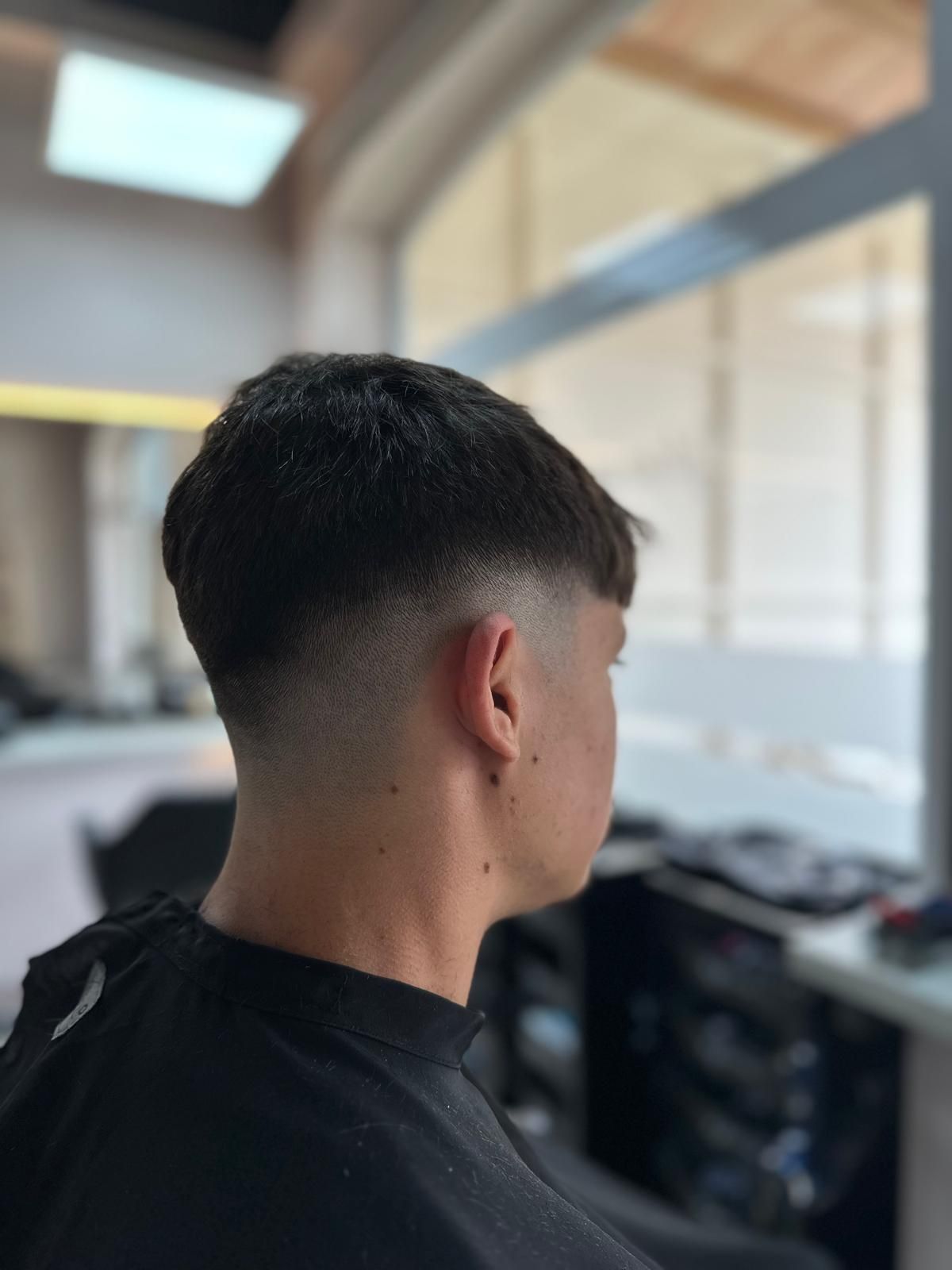 Un joven se está cortando el pelo en una barbería.