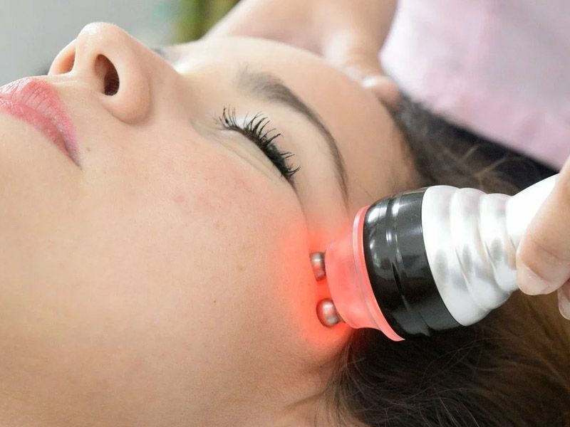 Una mujer recibe un tratamiento de luz roja en su cara.