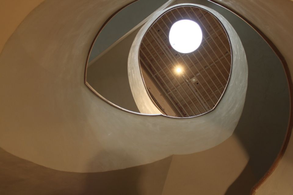 Blick nach oben auf eine Wendeltreppe mit einem Oberlicht an der Spitze.