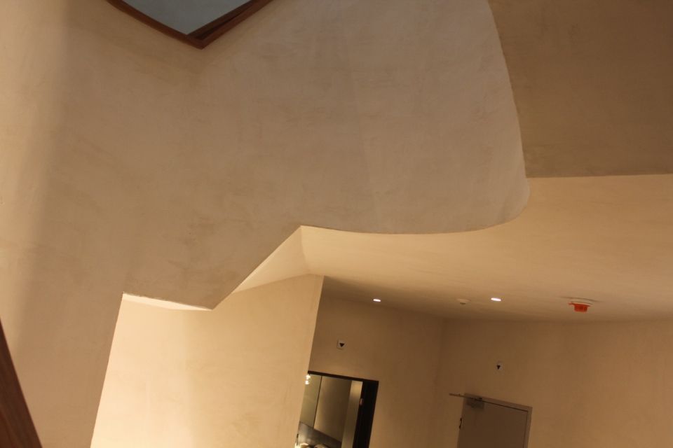 Innenansicht eines Gebäudes mit hellen Wänden und einem geschwungenen Deckenelement.