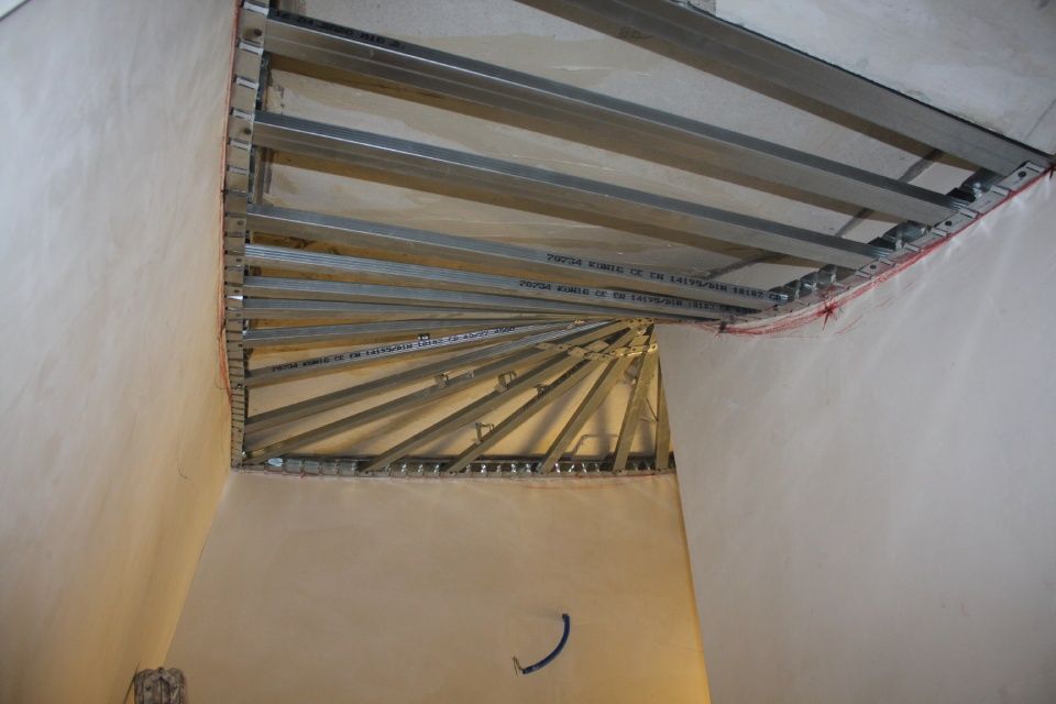 Metallgerüst einer im Bau befindlichen Wendeltreppe mit sichtbaren Stützen und Verkabelung.