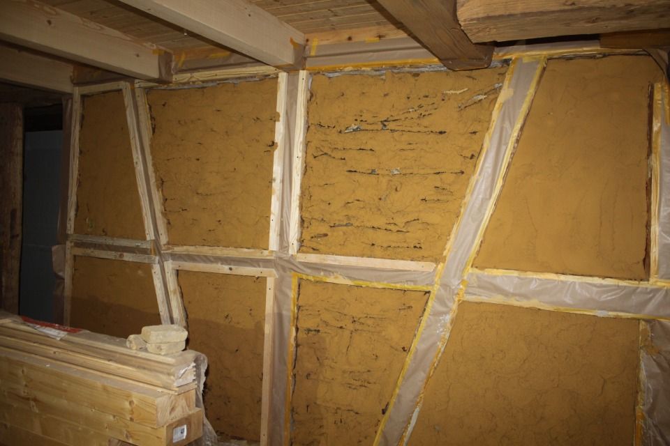 Innenwandkonstruktion: Sichtbares Fachwerk mit Lehmfüllung, hellbraune Farbtöne.