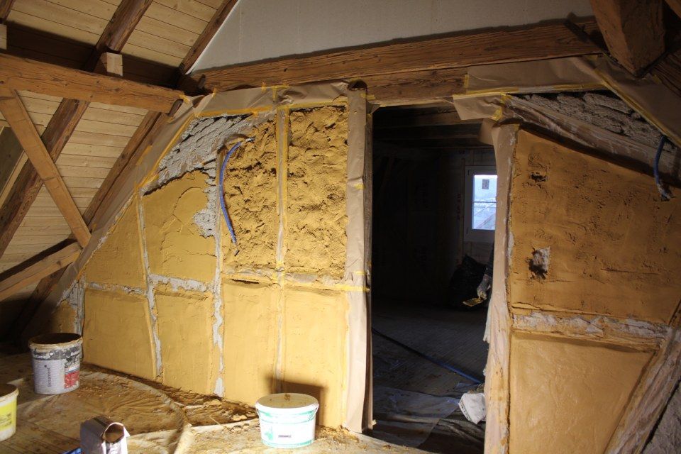 Im Bau befindliches Dachgeschosszimmer mit teilweise errichteten Wänden aus Naturmaterialien.
