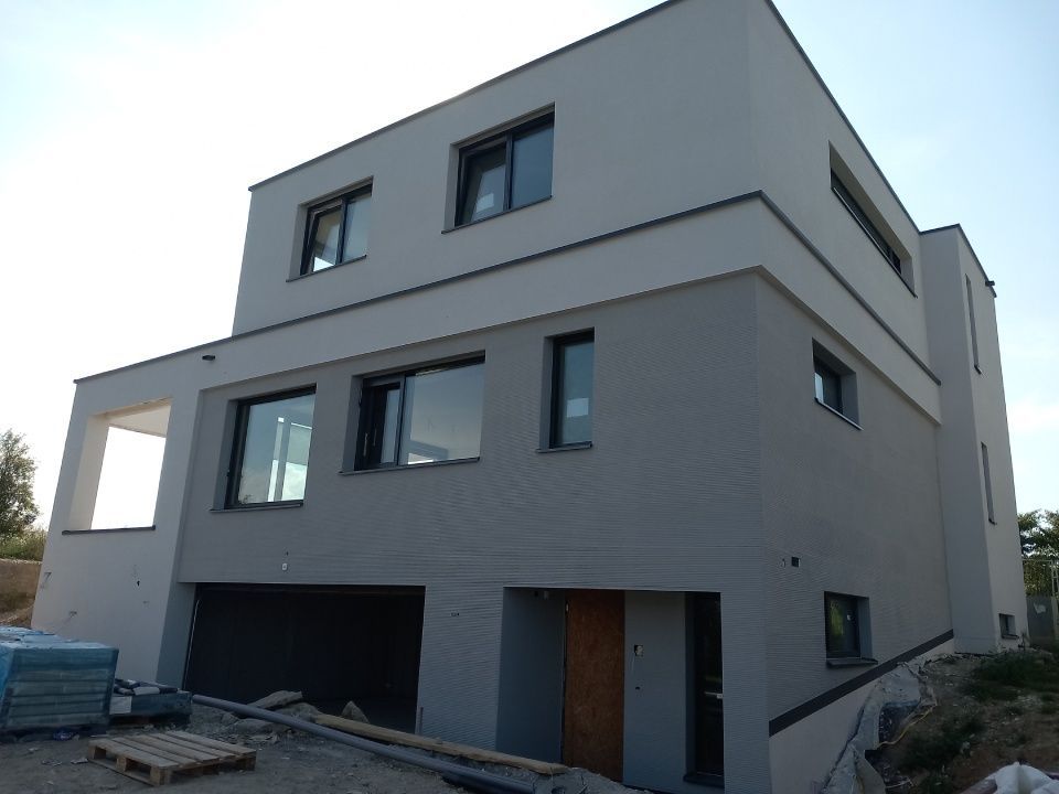 Modernes, zweistöckiges Haus im Bau mit hellgrauer und weisser Fassade.