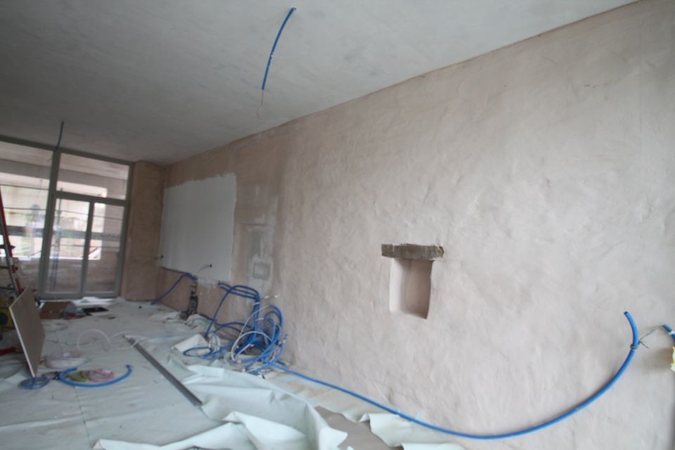 Innenraum im Bau, mit rosa strukturierten Wänden, blauer Verkabelung und einem eingelassenen Quadrat.