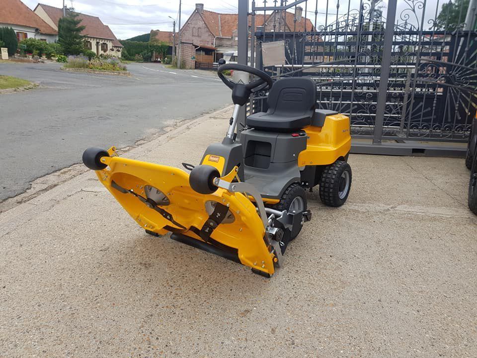 Tondeuse à gazon autoportée jaune garée dans une allée près d'une rue résidentielle