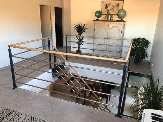 Mezzanine avec balustrade en verre, escalier et plantes en pot dans un intérieur de maison moderne et lumineux
