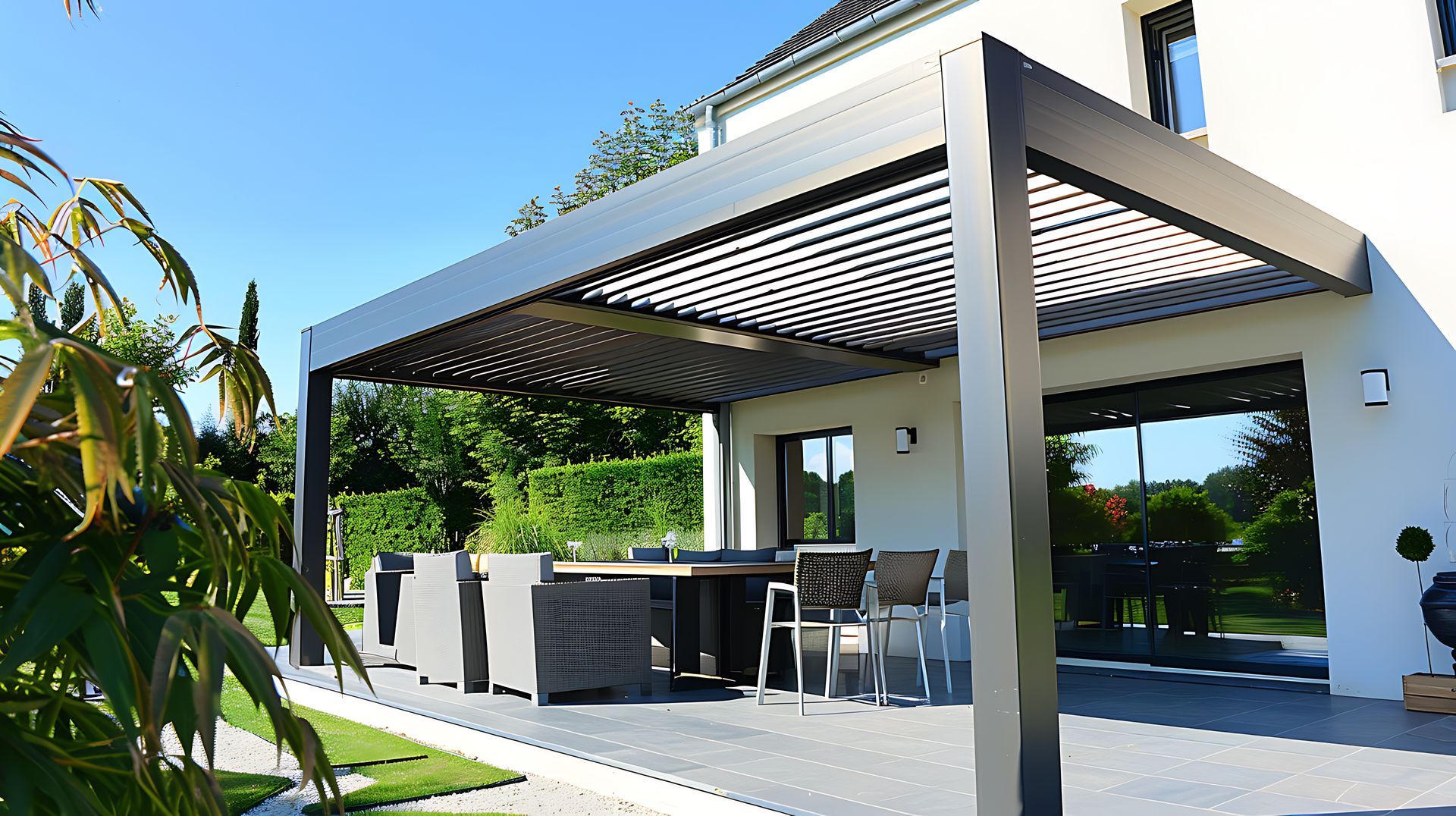 Patio moderne avec une pergola en bois, des chaises longues et une cour arrière gazonnée sous un ciel bleu azur.