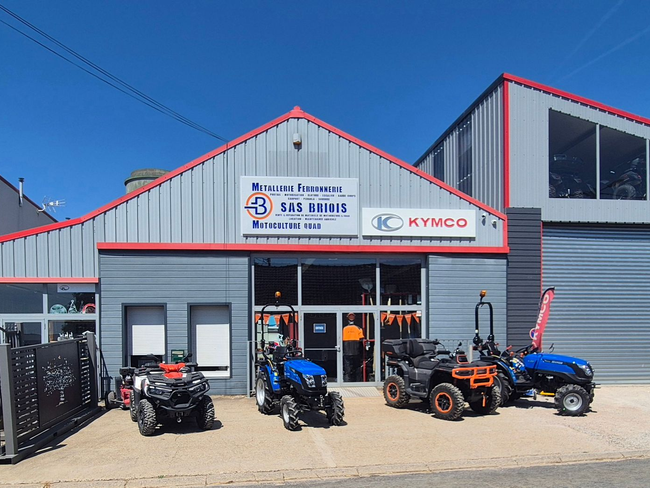 Des quads et un SSV exposés devant un magasin gris et rouge