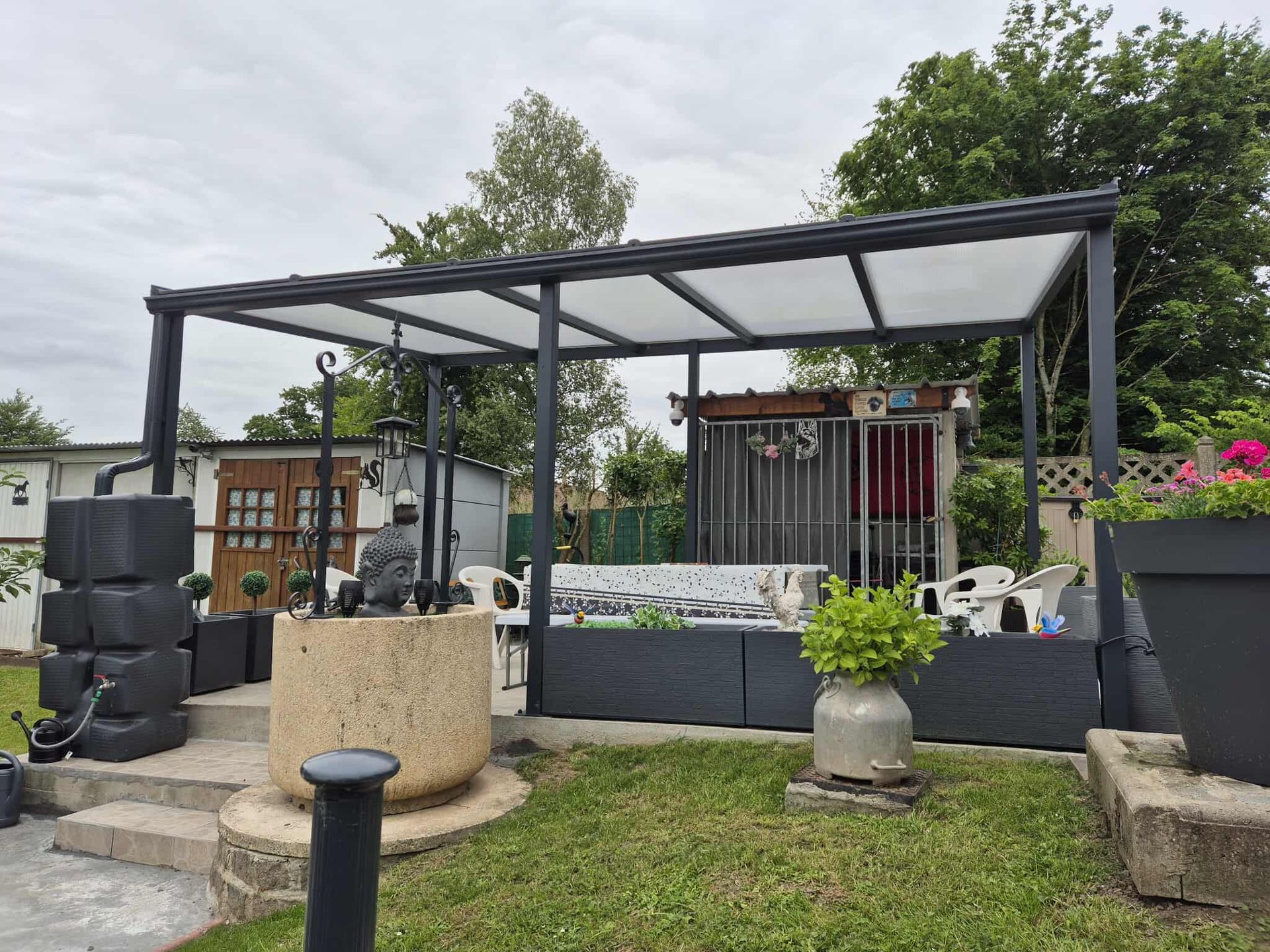 Patio moderne avec pergola, table à manger extérieure et chaises longues à côté d'une maison blanche par une journée ensoleillée
