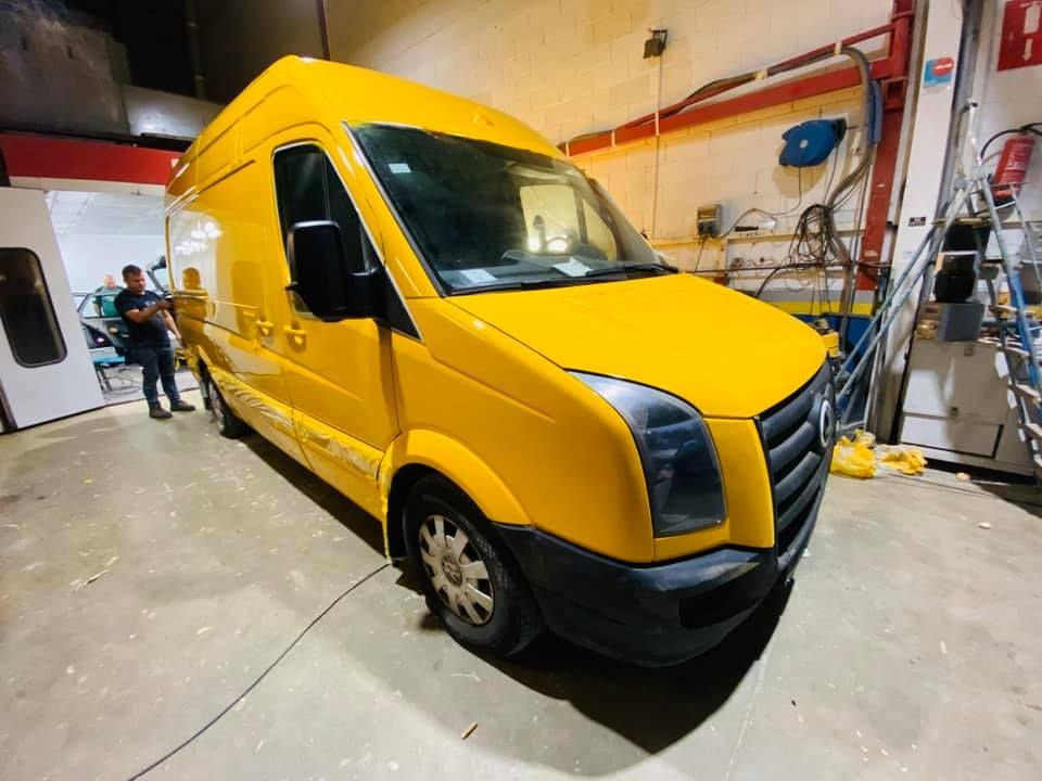 Furgoneta amarilla estacionada dentro de un garaje; una persona está cerca de la puerta abierta.