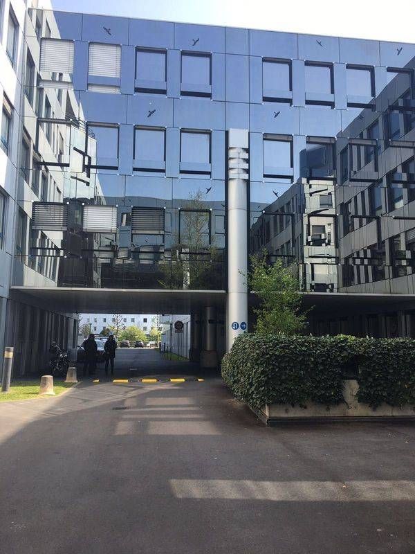 Cour intérieure moderne vitrée avec allée, pont et quelques personnes au loin