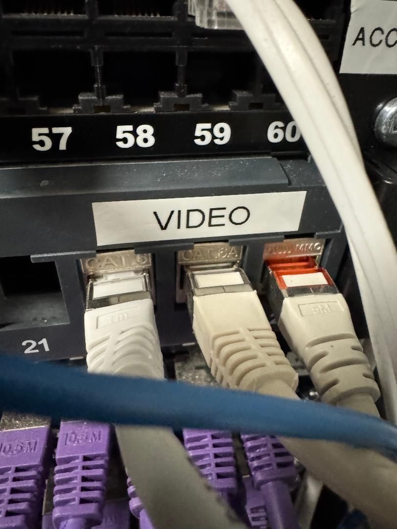 Ports du commutateur réseau étiquetés VIDEO avec câbles Ethernet blanc et violet connectés