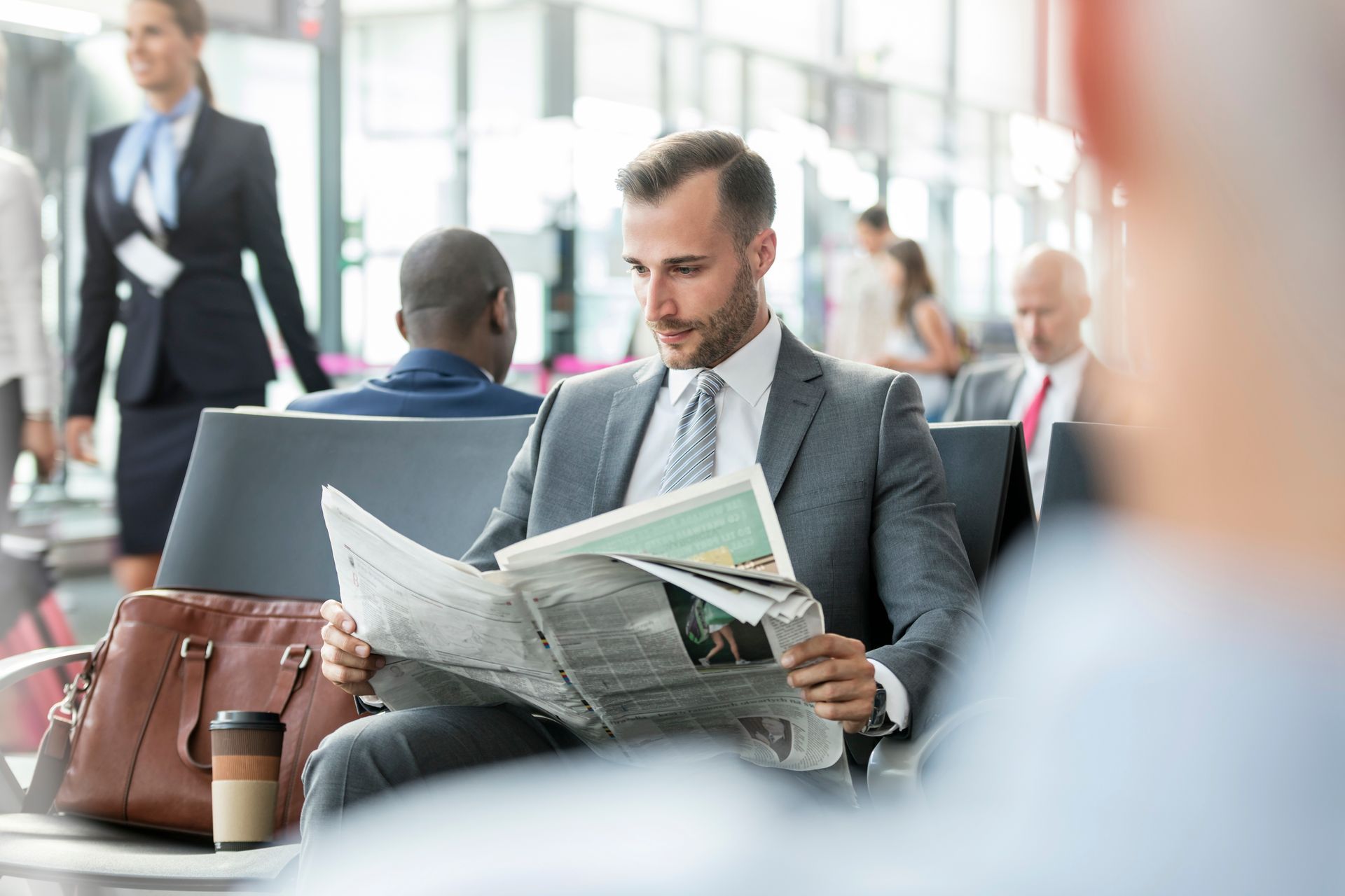 Un homme en costume lit le journal à l'aéroport