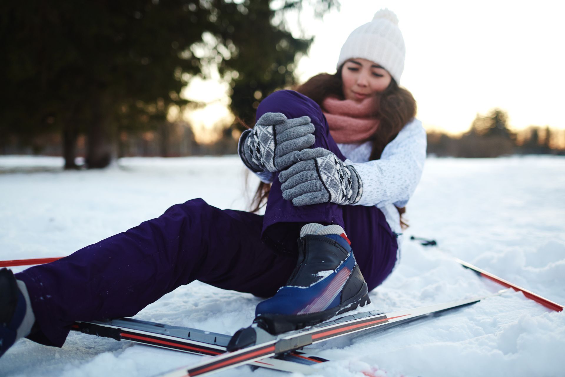 Jeune femme se tient la jambe suite à une chute en skis