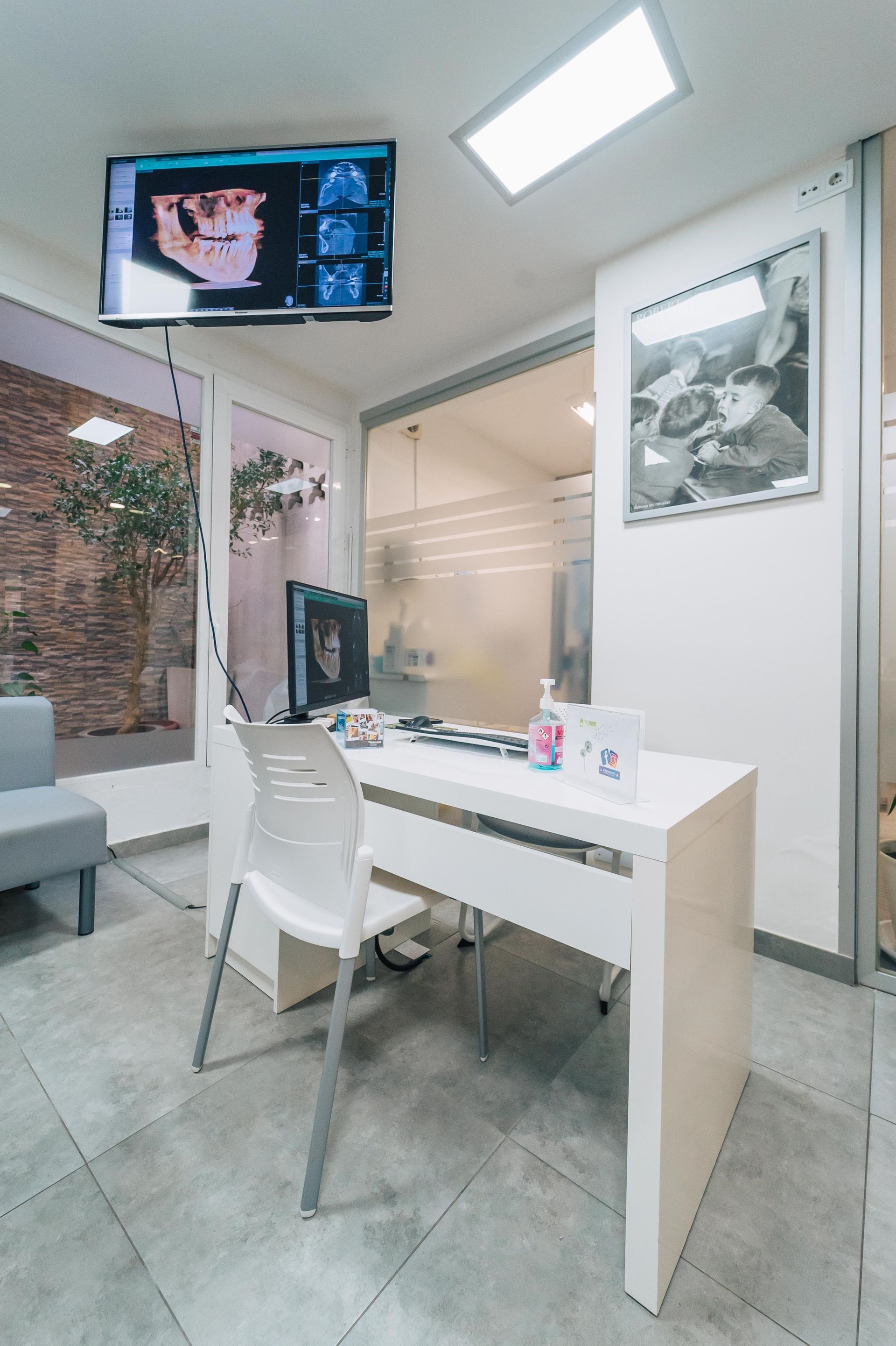 Un consultorio dental con un escritorio y sillas y un televisor colgando del techo.