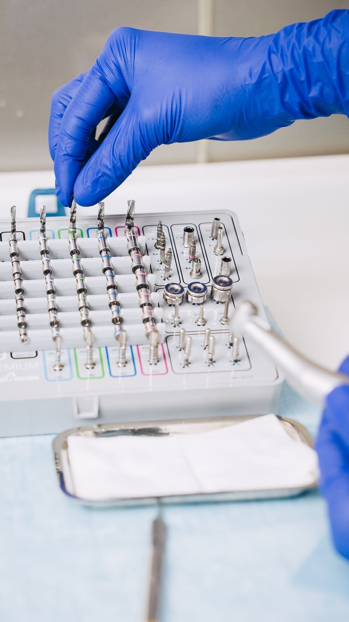 Una persona que lleva guantes azules sostiene una herramienta dental.