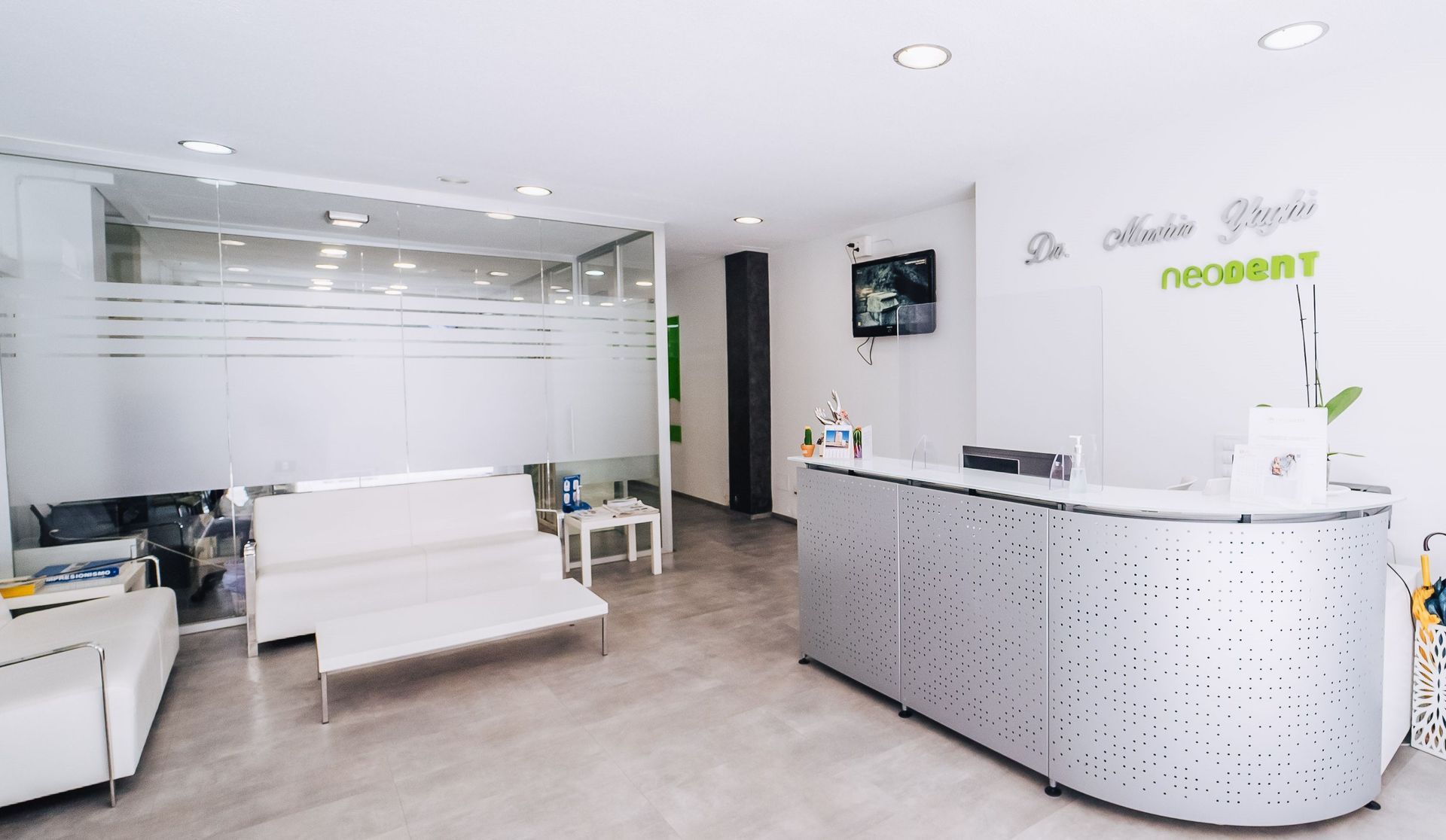 Una sala de espera con un sofá blanco y un mostrador plateado.