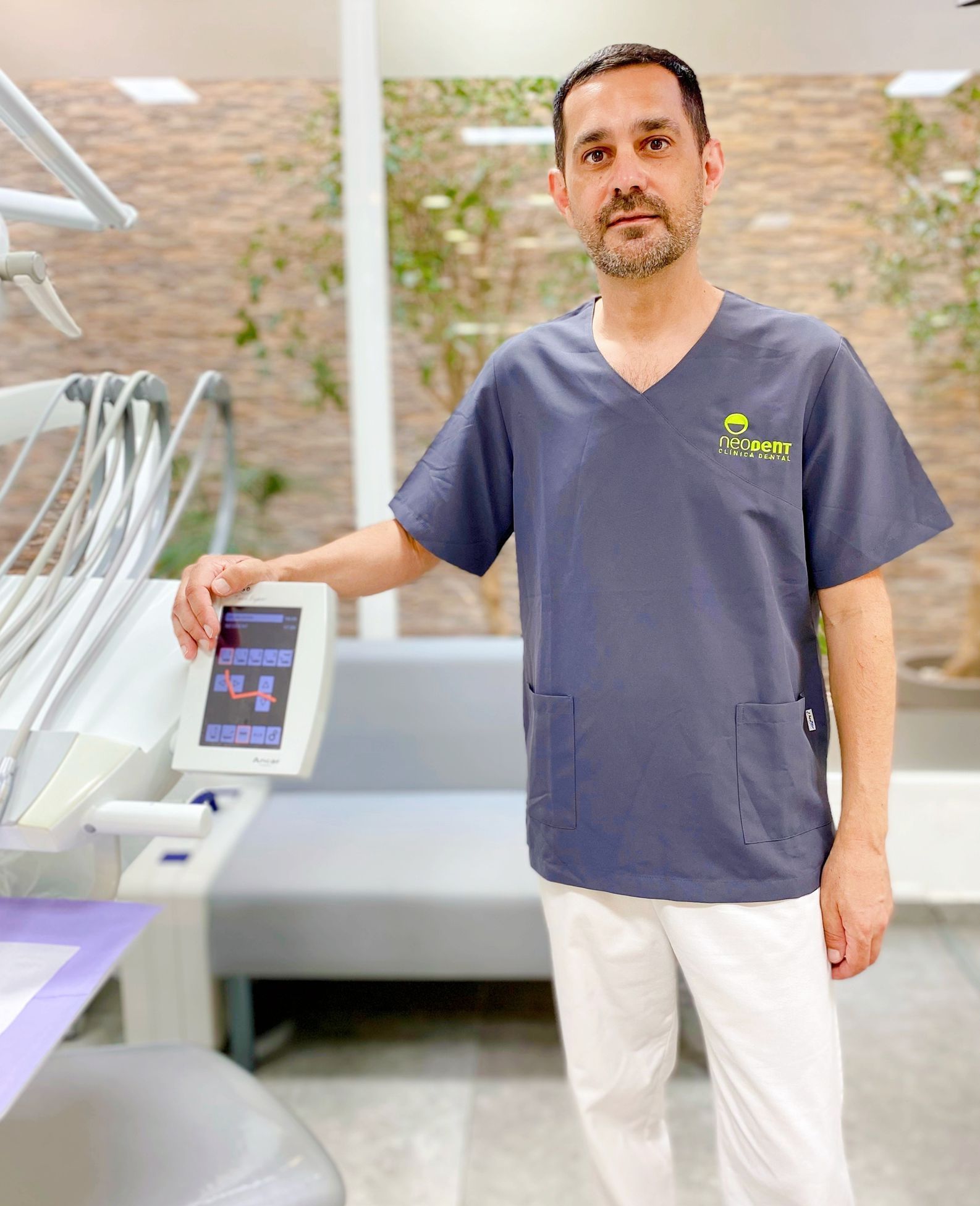 Un dentista está de pie en un consultorio dental sosteniendo un monitor.