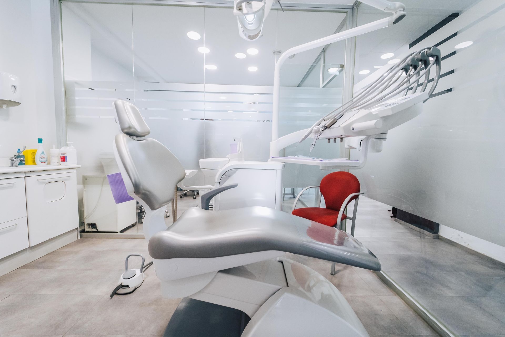 Un consultorio dental con un sillón dental y una silla roja.