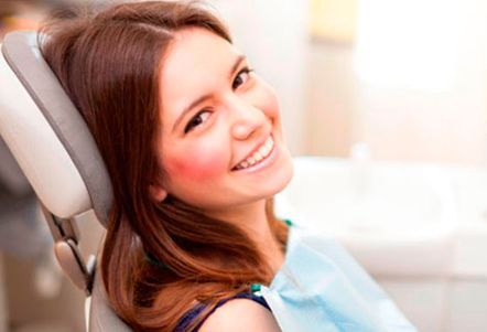 Una mujer sonríe mientras está sentada en una silla dental.