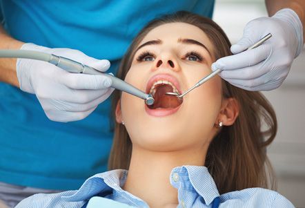Una mujer está siendo examinada por un dentista.