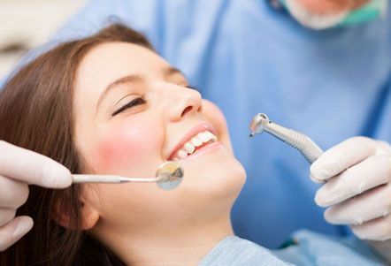 Una mujer está siendo examinada por un dentista.