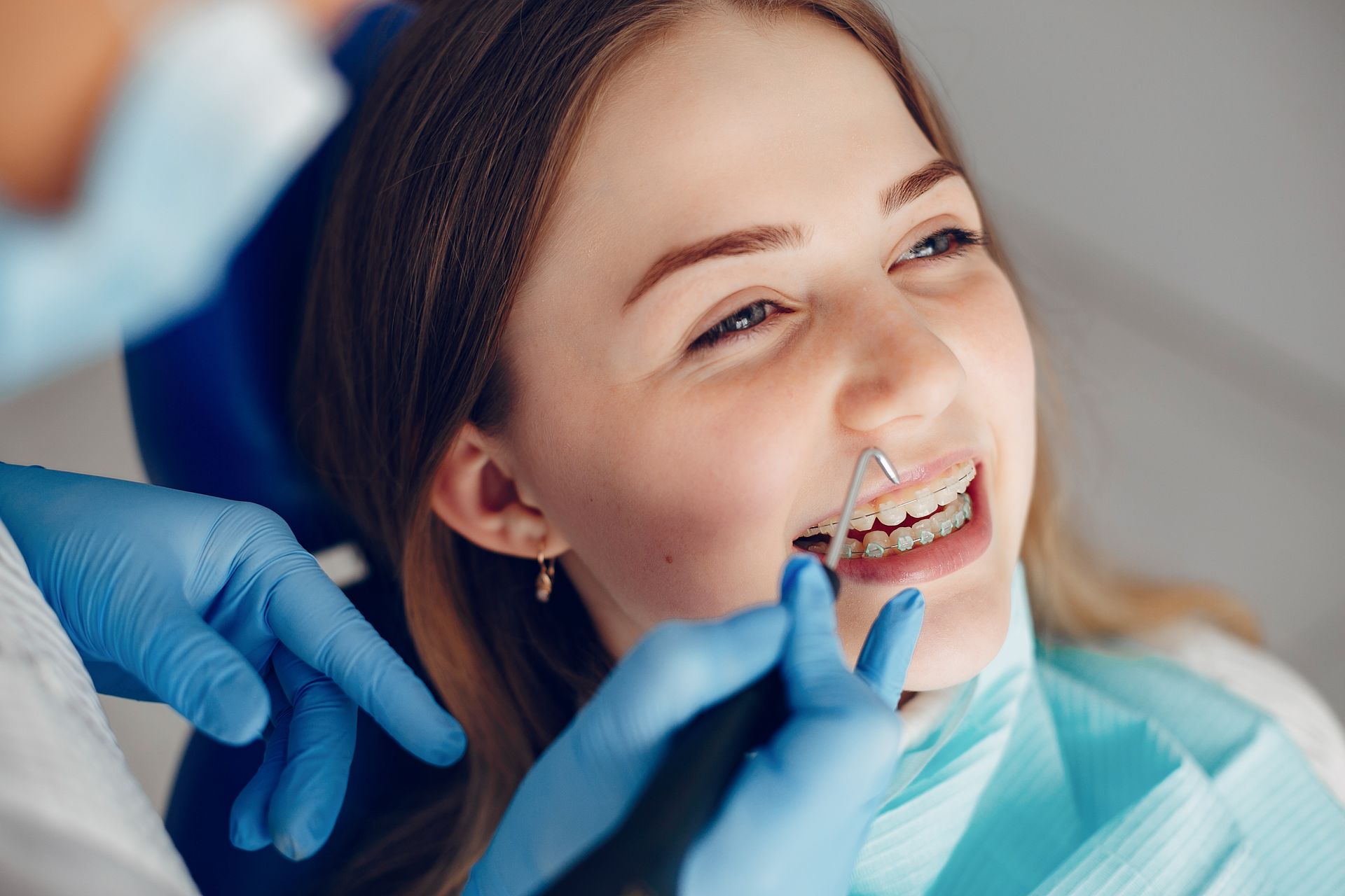 Una mujer está sentada en una silla dental mientras un dentista le examina los dientes.