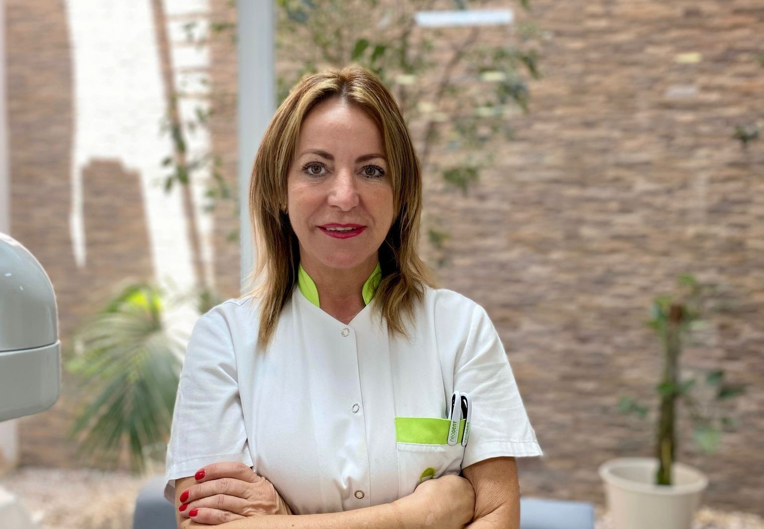 Una mujer con un uniforme blanco está de pie con los brazos cruzados.