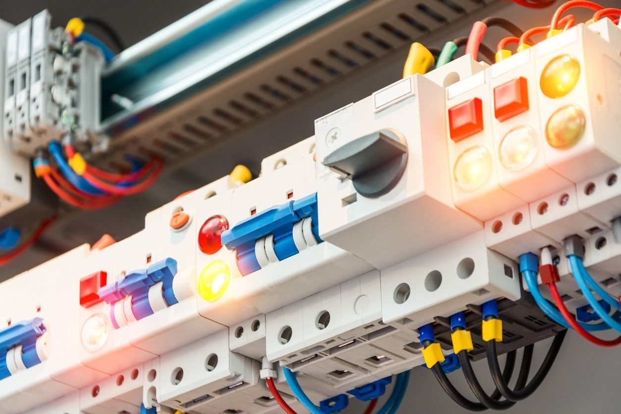 Panel de control eléctrico con disyuntores, cables y luces, en un entorno industrial.