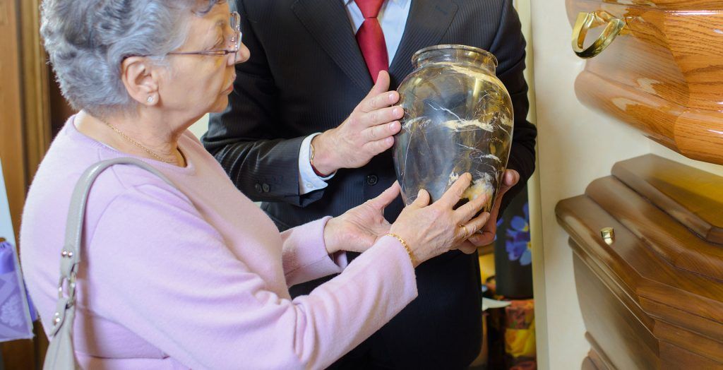 Dame âgée prend en main une urne funéraire