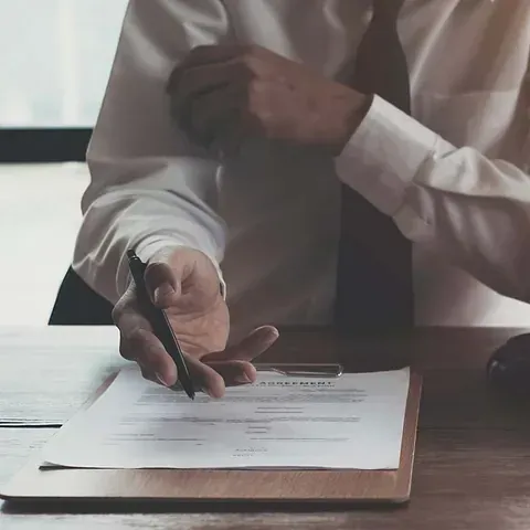 Un hombre está escribiendo en un portapapeles con un bolígrafo.