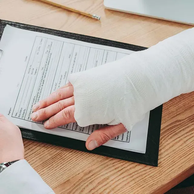 Una persona con un yeso en el brazo está firmando un documento.