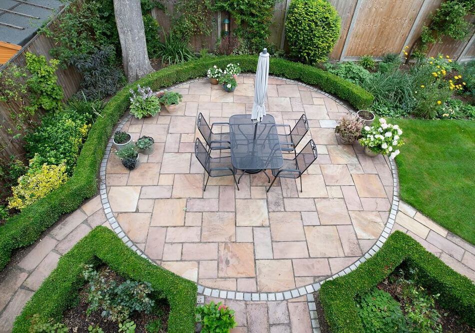 Luftaufnahme einer Terrasse mit Tisch und Stühlen in einem Garten.