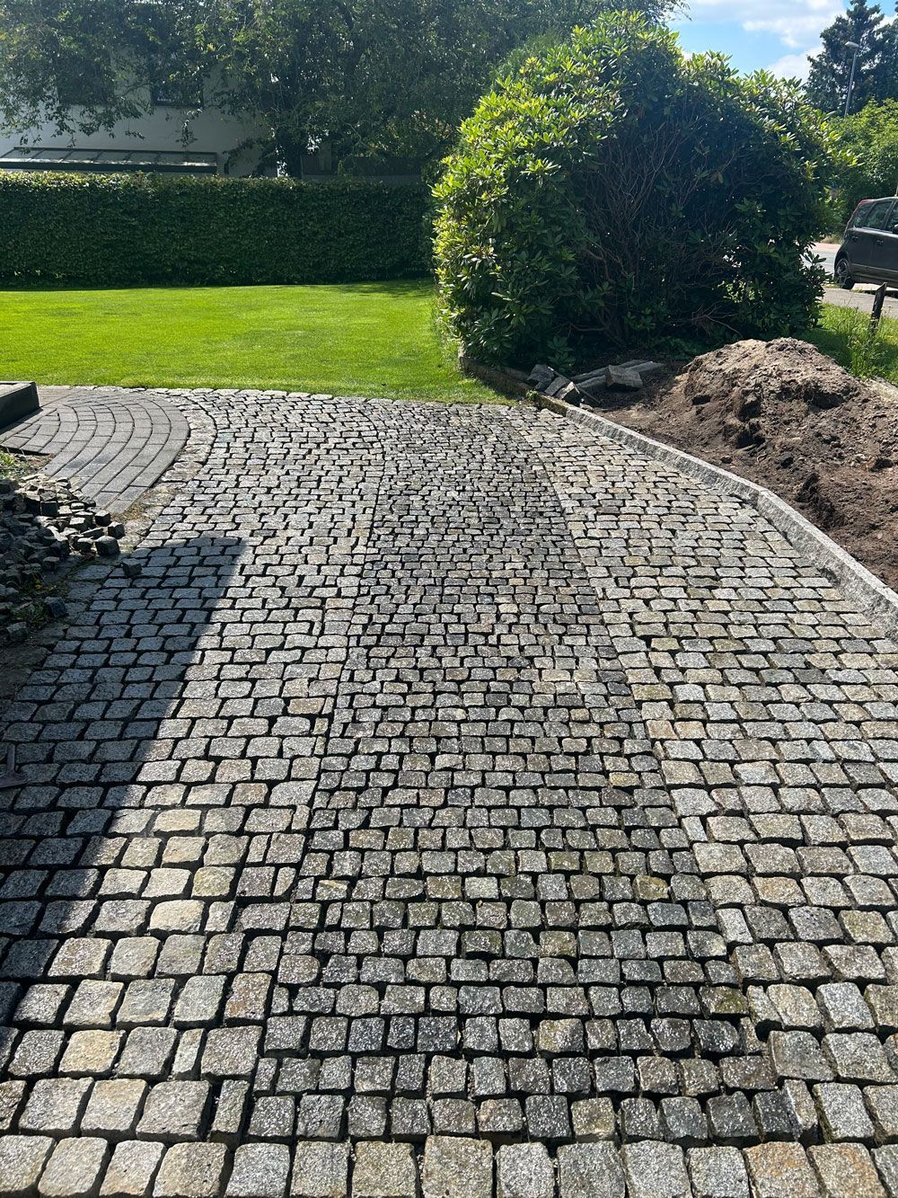 Eine gepflasterte Auffahrt, die zu einem üppigen grünen Rasen führt.