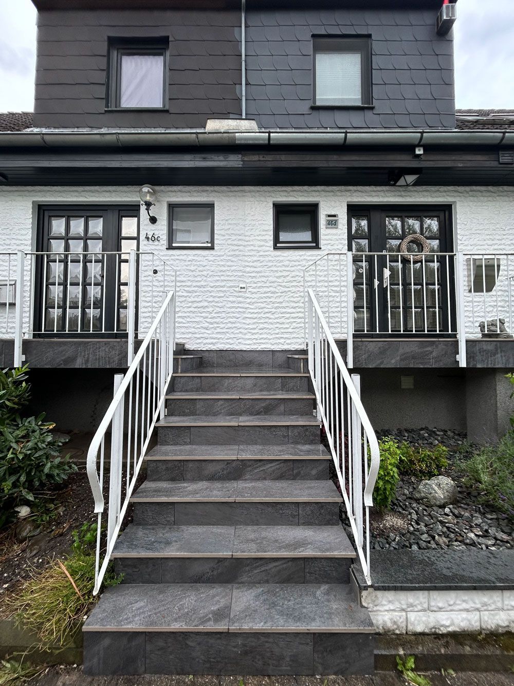 Ein weißes Backsteinhaus mit Treppen, die zur Haustür hinaufführen.