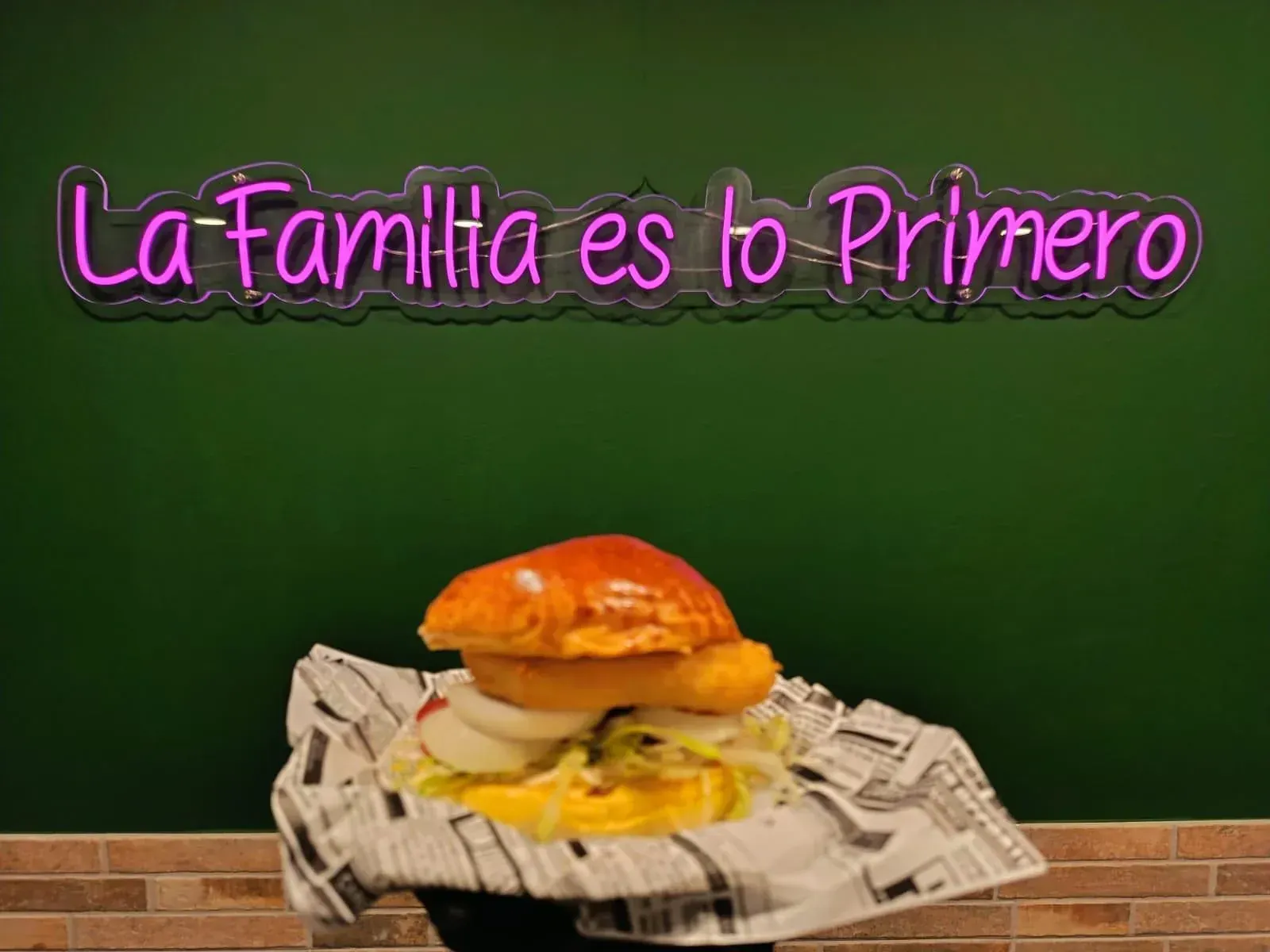 Sándwich de salchicha en un plato blanco con texto, en un entorno de cafetería.