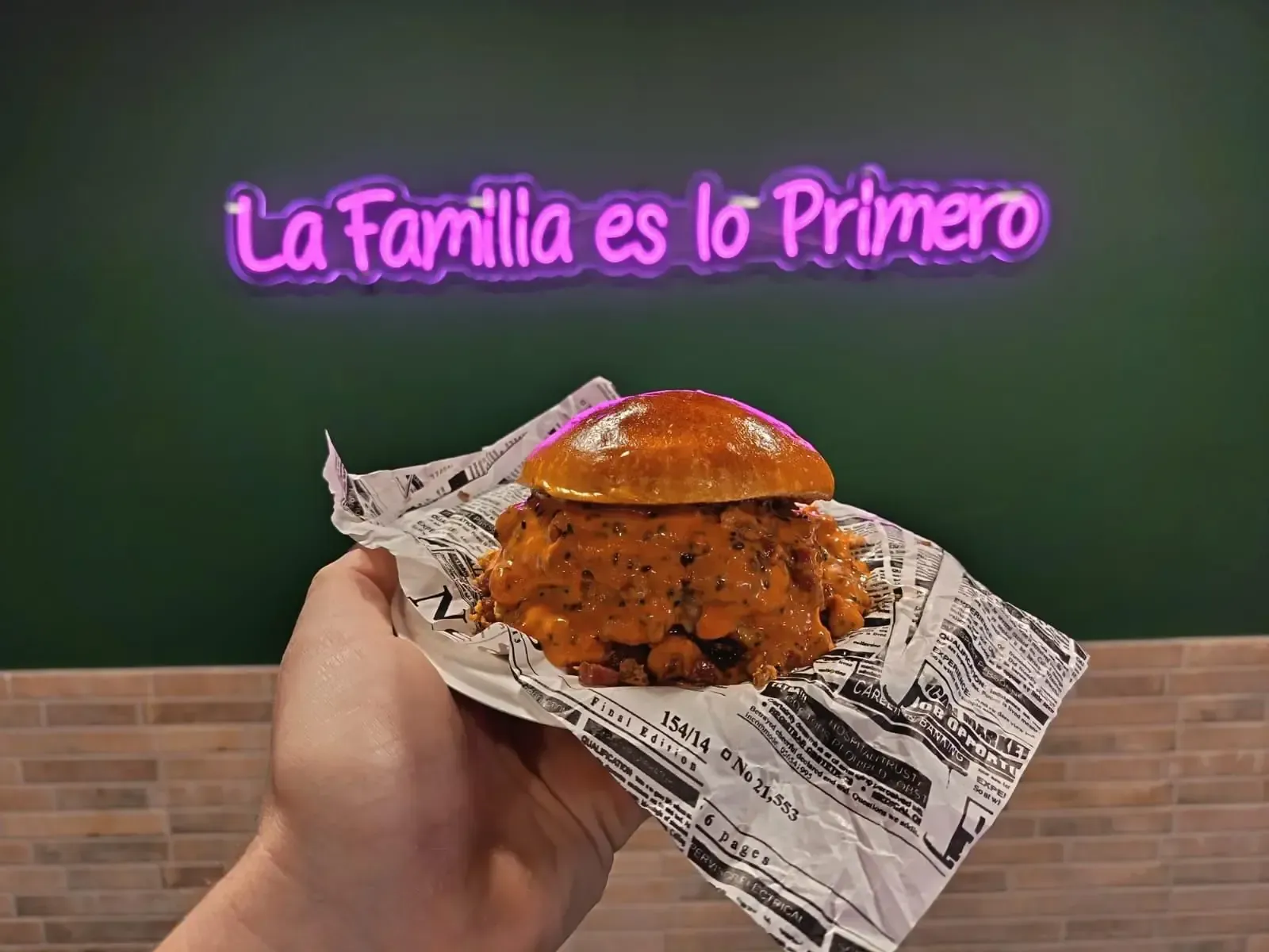 Sándwich de salchicha en un plato blanco con texto, en un entorno de cafetería.