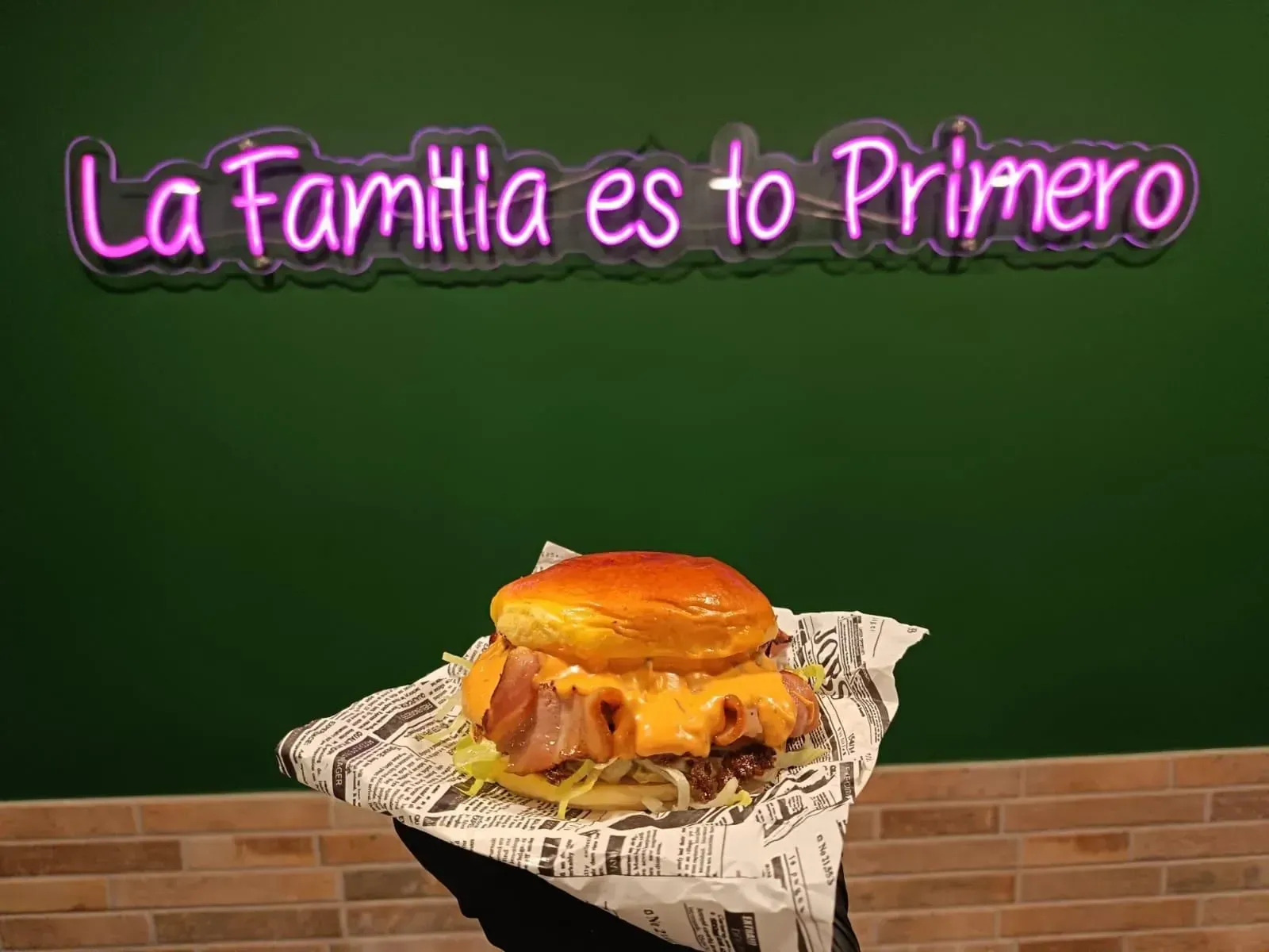 Sándwich de salchicha en un plato blanco con texto, en un entorno de cafetería.