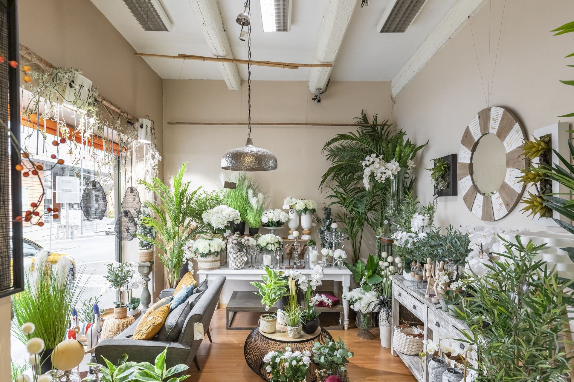 Boutique lumineuse remplie de plantes, avec des plantes en pot, des fleurs et un grand miroir mural