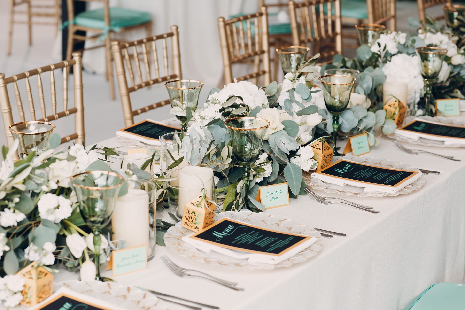 Élégante table de réception de mariage blanche et menthe, ornée de compositions florales, de bougies et de chaises dorées