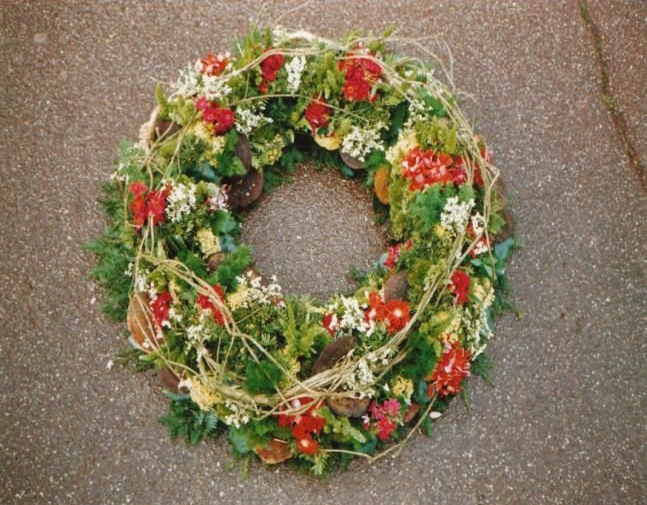Couronne florale rouge et blanche avec de la verdure sur un fond goudronné