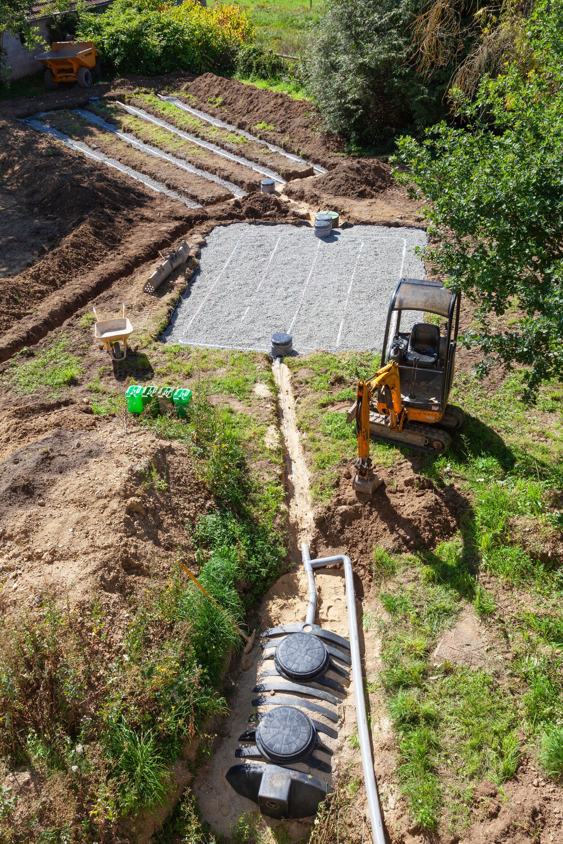 Une tractopelle sur un terrain en train de creuser avec une fosse toutes eaux enterrée